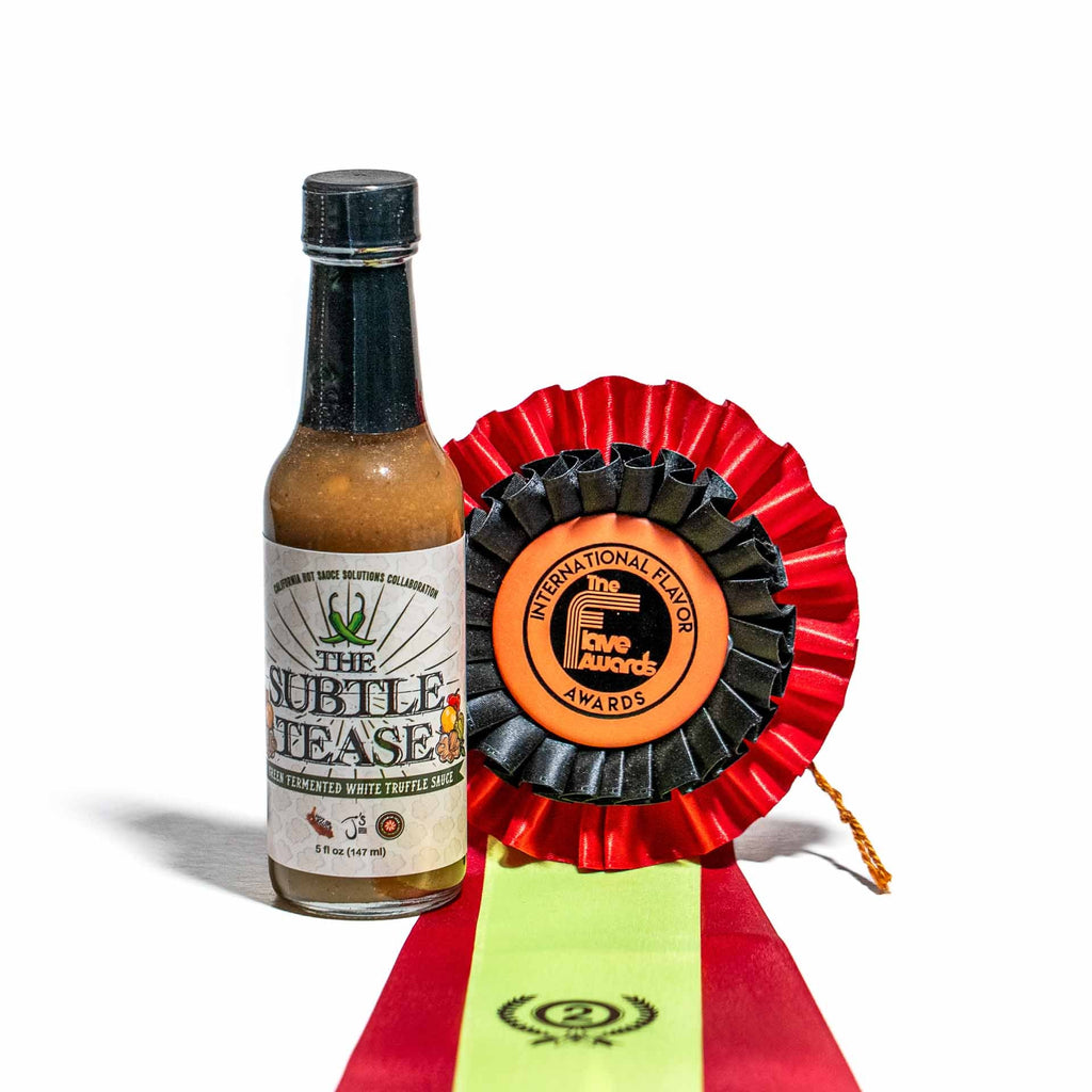 Hot sauce bottle labeled 'The Subtle Tease' with a red ribbon award on a white background