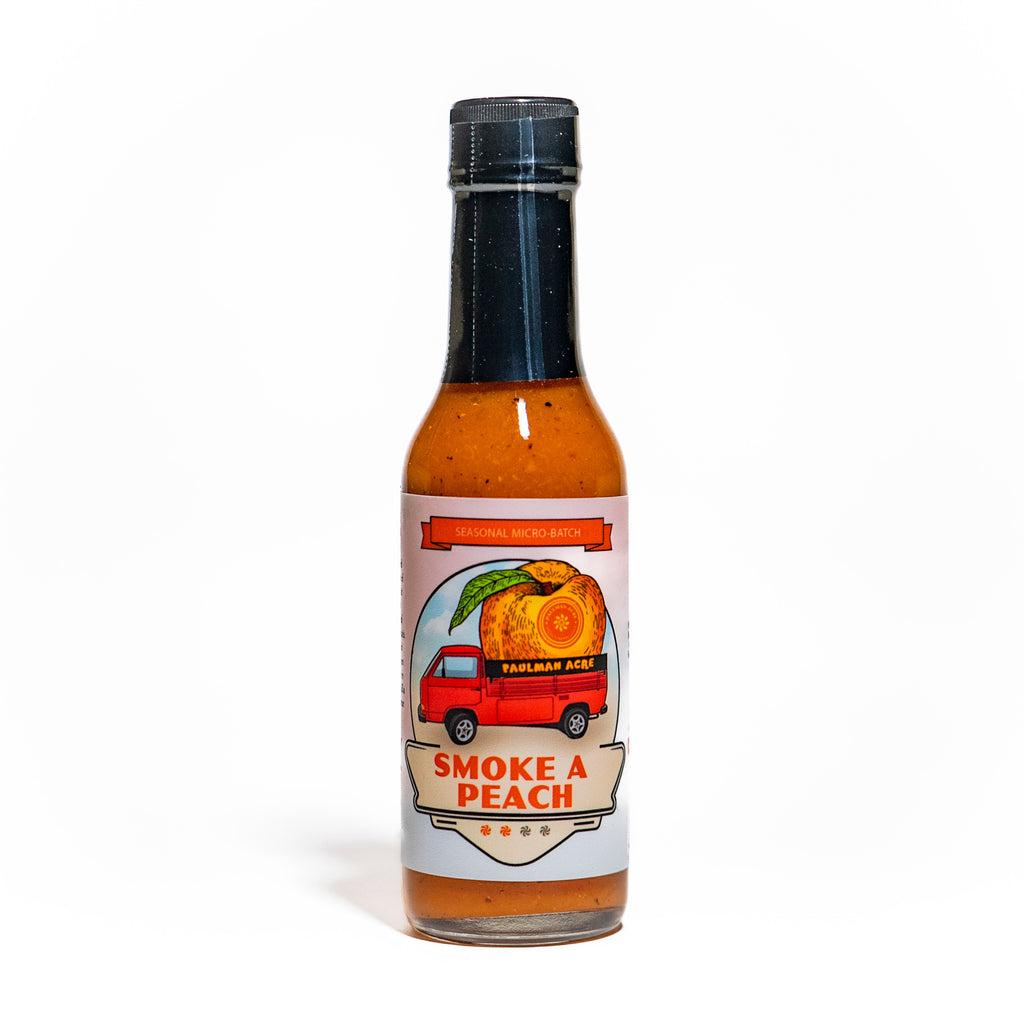 Bottle of Smoke a Peach hot sauce with a label featuring a peach and a truck on a white background.